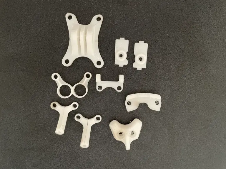 Mehrere kleine weiße 3D-gedruckte Teile auf dunklem Untergrund