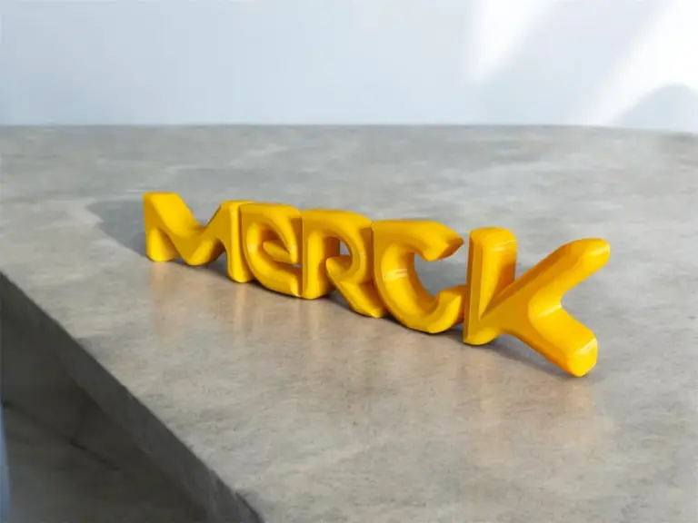 Gelber 3D-gedruckter Logo-Schriftzug, freistehend auf einer Steinplatte