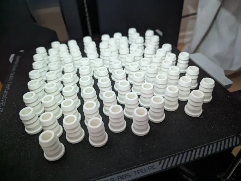 Viele weiße 3D-gedruckte Kleinteile auf einer Druckplatte
