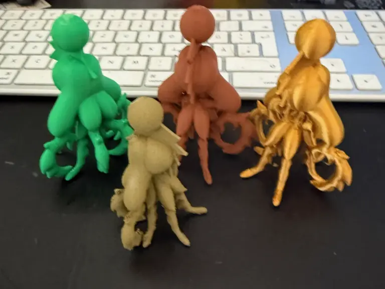 Vier 3D-gedruckte Figuren in Grün, Braun, Beige und Gold