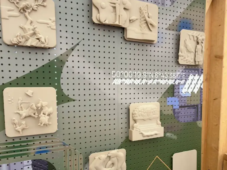 Mehrere helle 3D-gedruckte Reliefs an einer Ausstellungswand