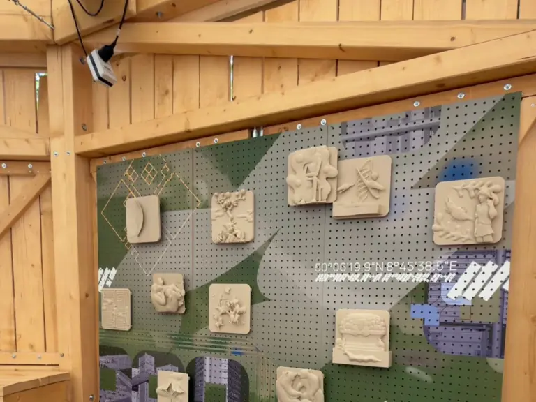 Helle 3D-gedruckte Relieftafeln an einer Lochwand in einer Ausstellung