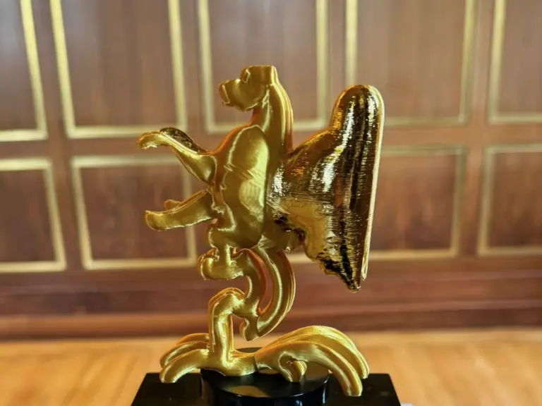 Goldfarbene 3D-gedruckte Skulptur auf einem Sockel in einem holzgetäfelten Raum