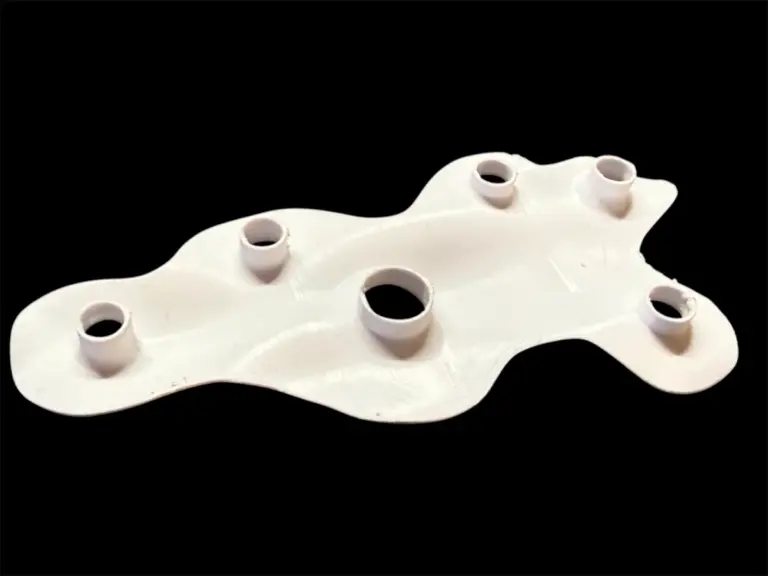Weißes 3D-gedrucktes Freiformteil mit mehreren Bohrungen