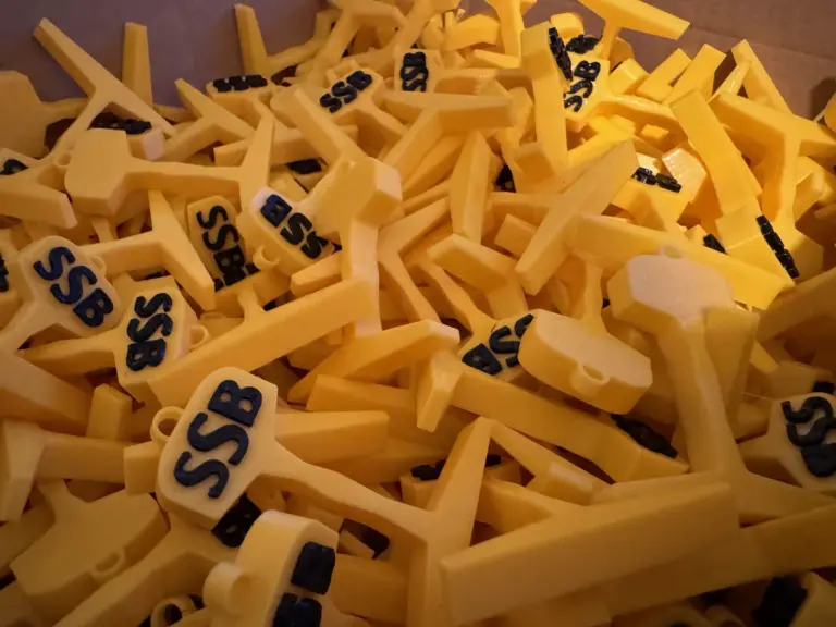 Viele gelbe 3D-gedruckte Schlüsselanhänger in Form eines Schienenquerschnitts